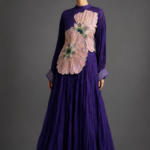 Luxury royal purple Indo-Western dress with oversized blush floral appliqué embroidery, intricate beadwork, full sleeves and flowing crinkled silhouette.