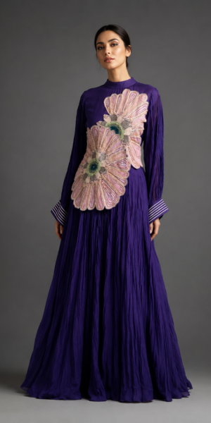Luxury royal purple Indo-Western dress with oversized blush floral appliqué embroidery, intricate beadwork, full sleeves and flowing crinkled silhouette.