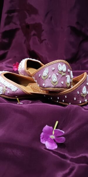 Blush pink handcrafted Punjabi jutti with white pearl beadwork, gold floral embroidery, and a comfortable flat sole for festive and wedding wear.