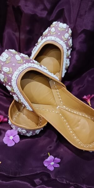 Blush pink handcrafted Punjabi jutti with white pearl beadwork, gold floral embroidery, and a comfortable flat sole for festive and wedding wear.