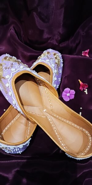 Lavender handcrafted Punjabi jutti with embroidered bird motifs, white pearl beadwork, gold zari embroidery, and a comfortable flat sole for festive and wedding wear.