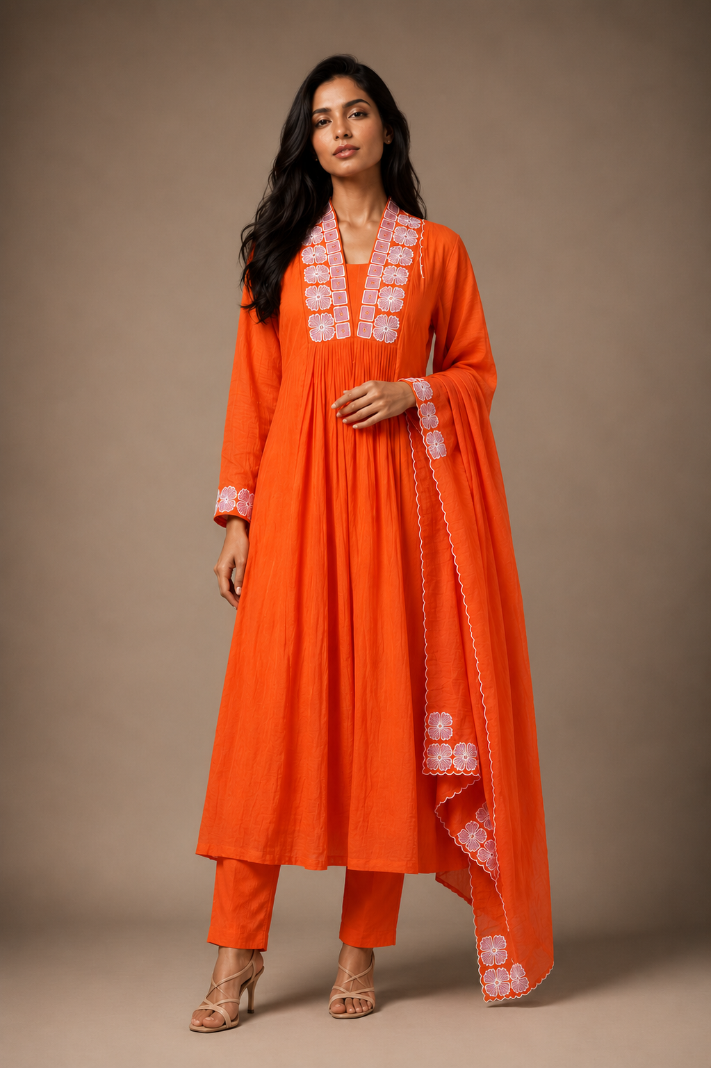 orange dress a saffron orange embroidered three-piece suit set featuring a gathered A-line kurta, straight cigarette pants, and a lightweight embroidered scalloped dupatta in a luxury studio setting.