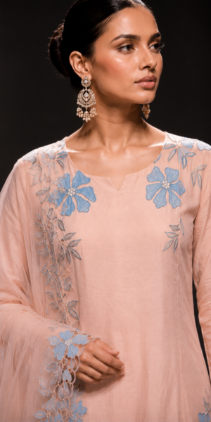 Blush pink muslin silk straight kurta set with blue floral appliqué embroidery, straight-leg pants, and organza dupatta featuring handcrafted floral cutwork border